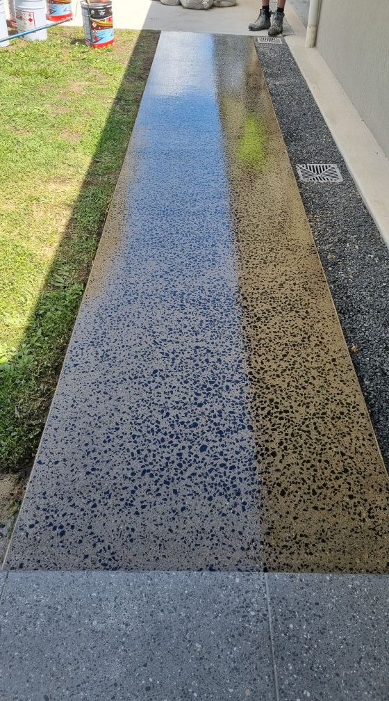 Narrow smooth concrete path with a freshly sealed strip showing the stone aggregate