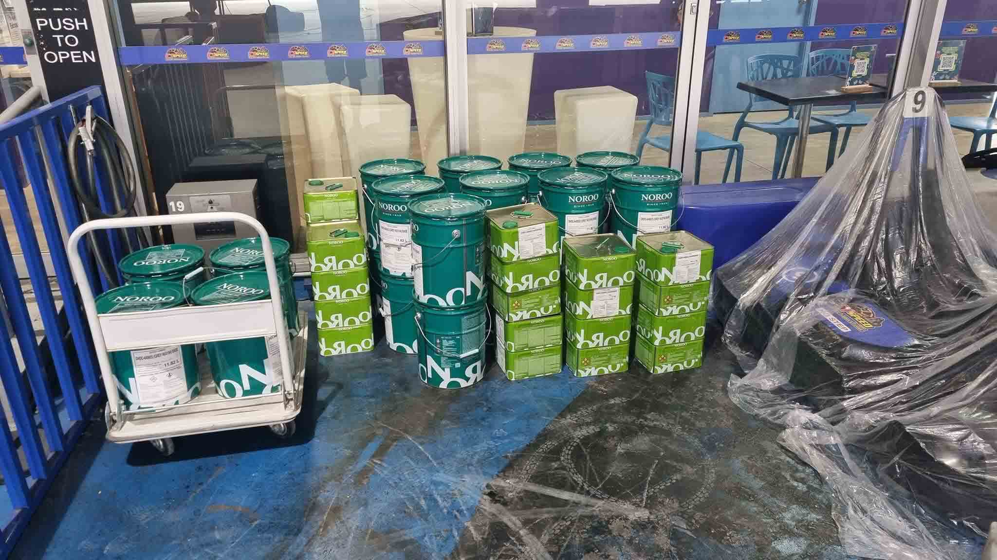 Noroo coating pails and tins stacked on and beside a trolley