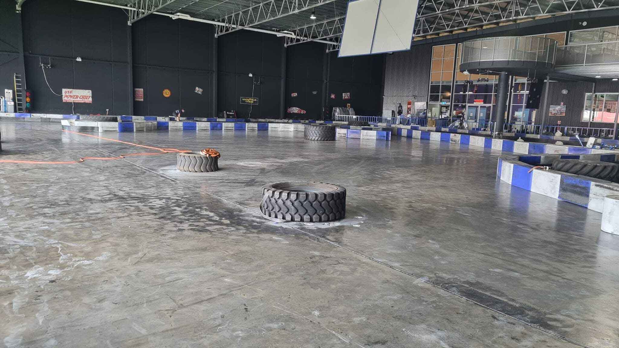 Indoor kart track floor partly cleaned, with tyres resting on the concrete