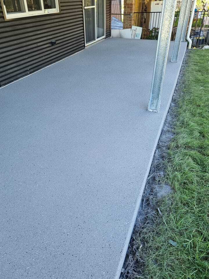 Resurfaced veranda with a speckled grey finish beside a lawn and posts