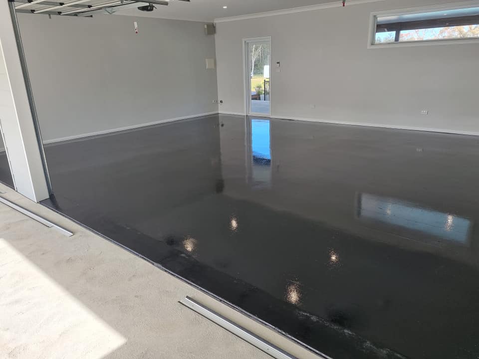Glossy dark grey floor coating reflecting the light in an empty garage