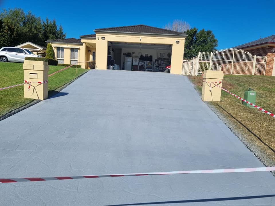 Resurfaced grey driveway leading up to a double garage, taped off
