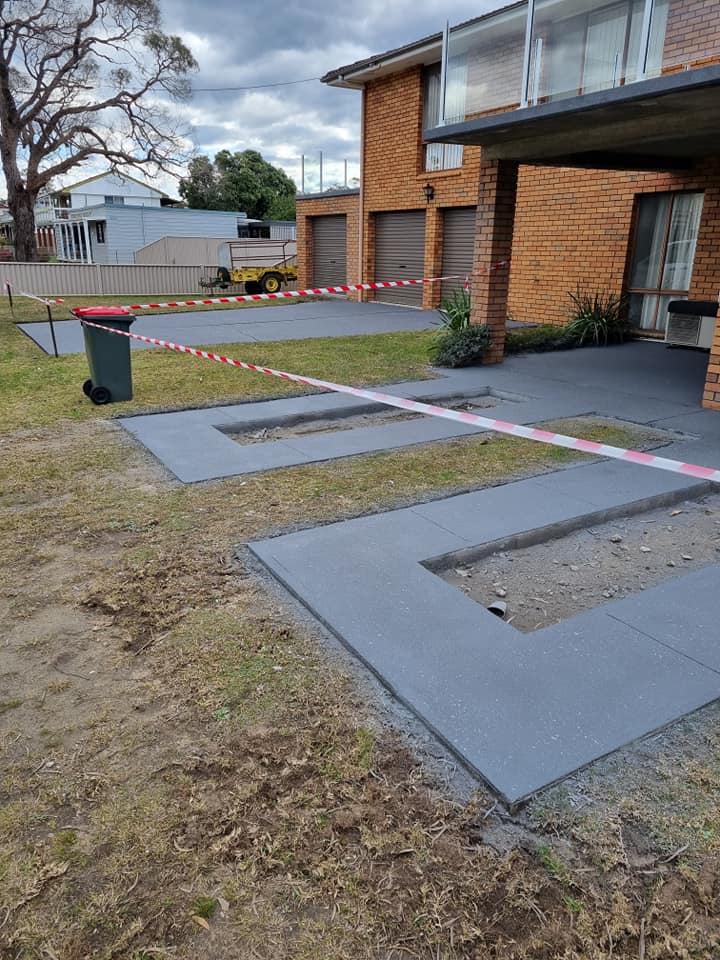 Charcoal ribbon driveway strips outside a two-storey brick house