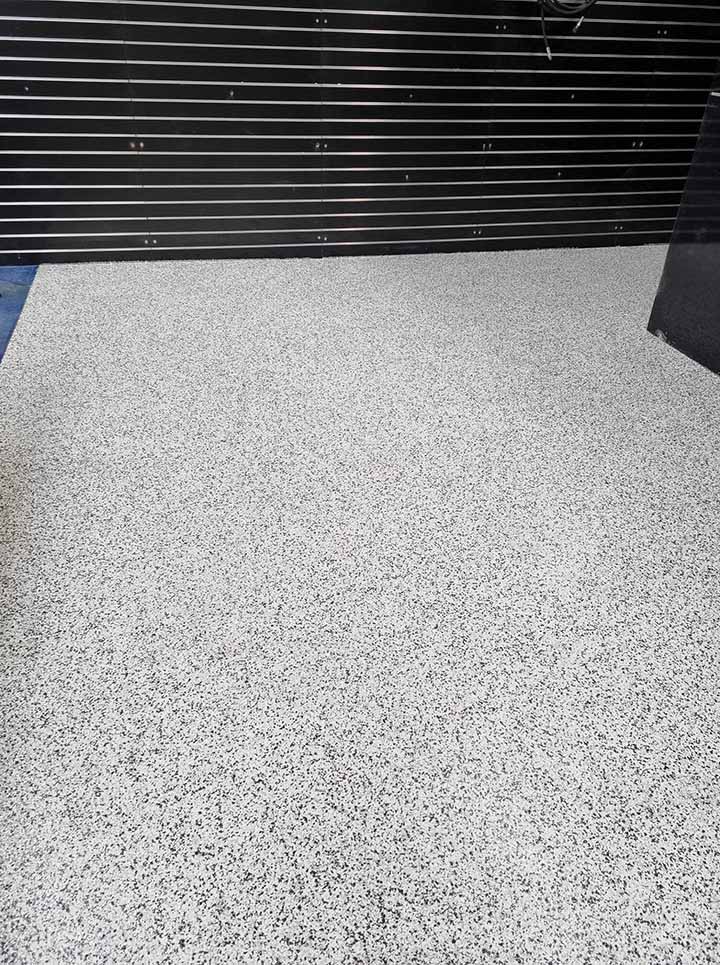 Second view of the white and grey flake floor coating by a slatted screen