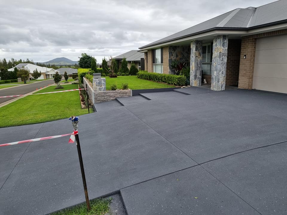 Charcoal driveway at a new brick home with stone-clad pillars, taped off