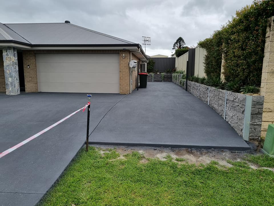 Charcoal driveway running down the side of a new brick home