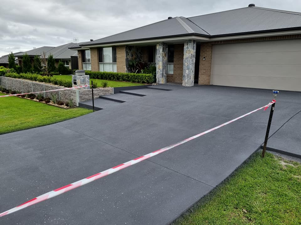 Charcoal driveway at a new brick home, viewed from the street with tape across