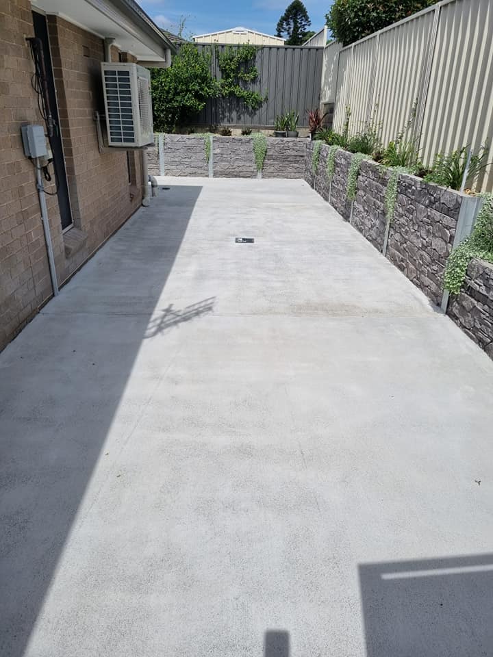 Concrete side path between a brick house and a stone retaining wall