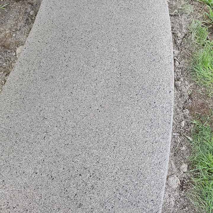 Close-up of a curved smooth concrete path edge beside grass
