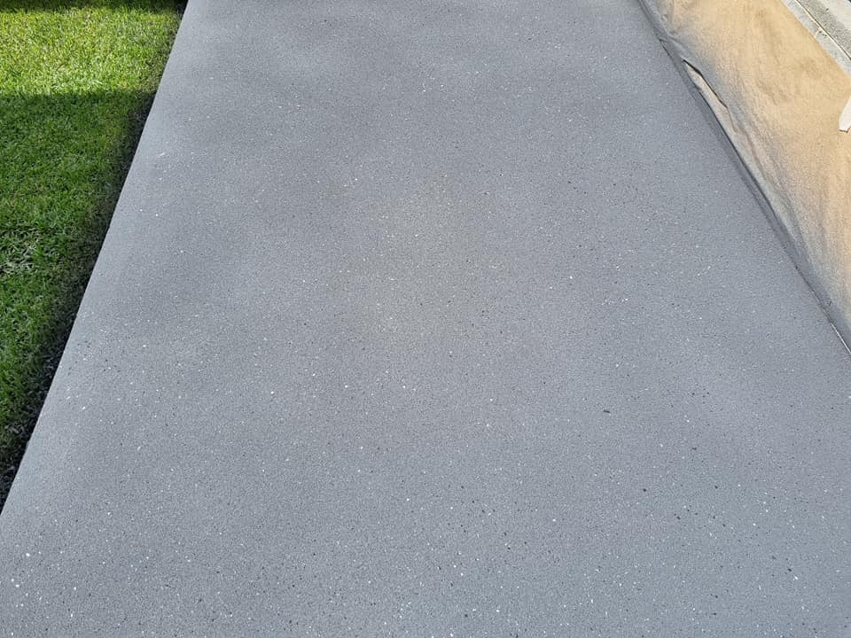 Grey resurfaced concrete path running beside a lawn