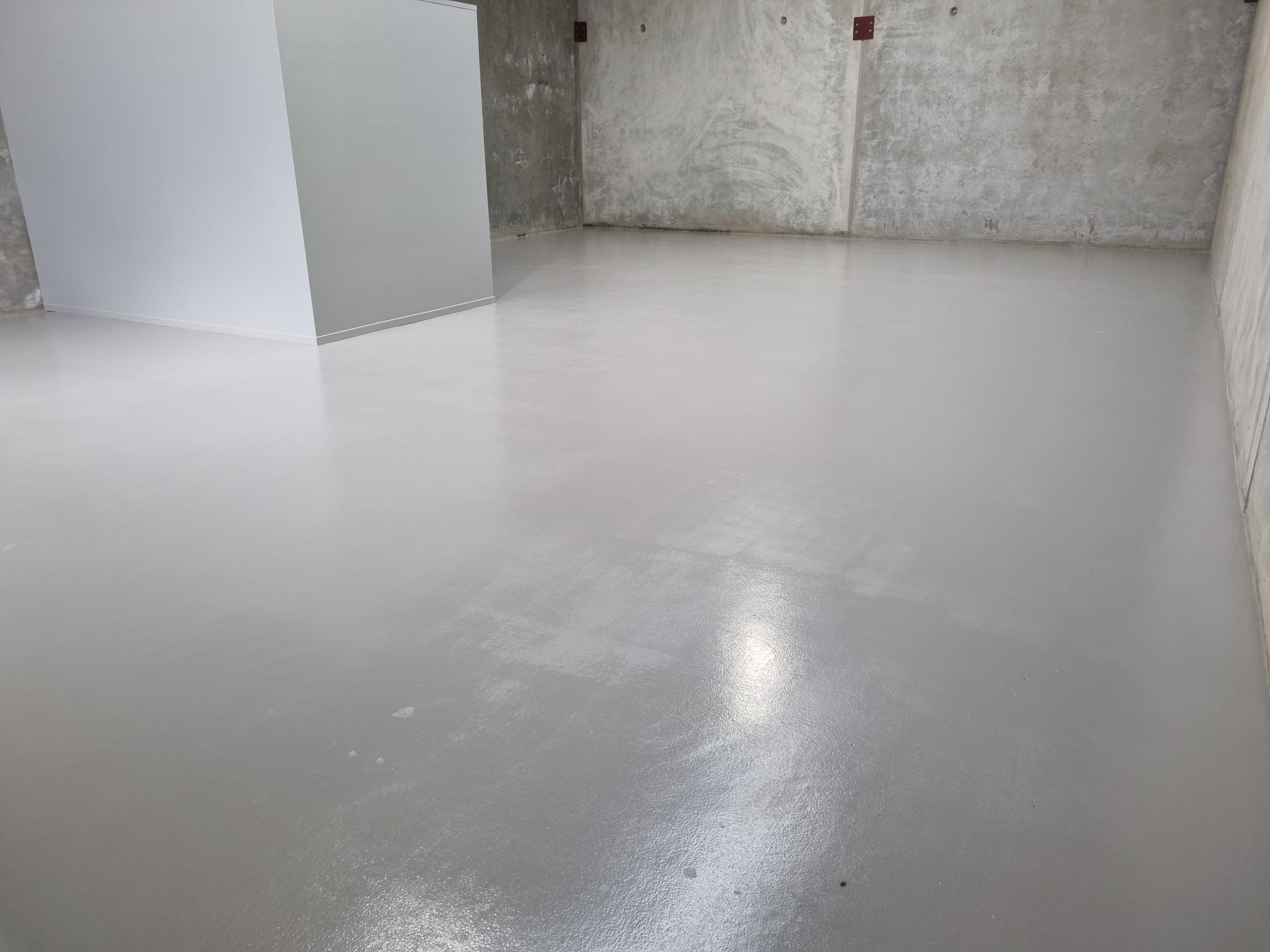 Light grey floor coating in an empty concrete-walled room