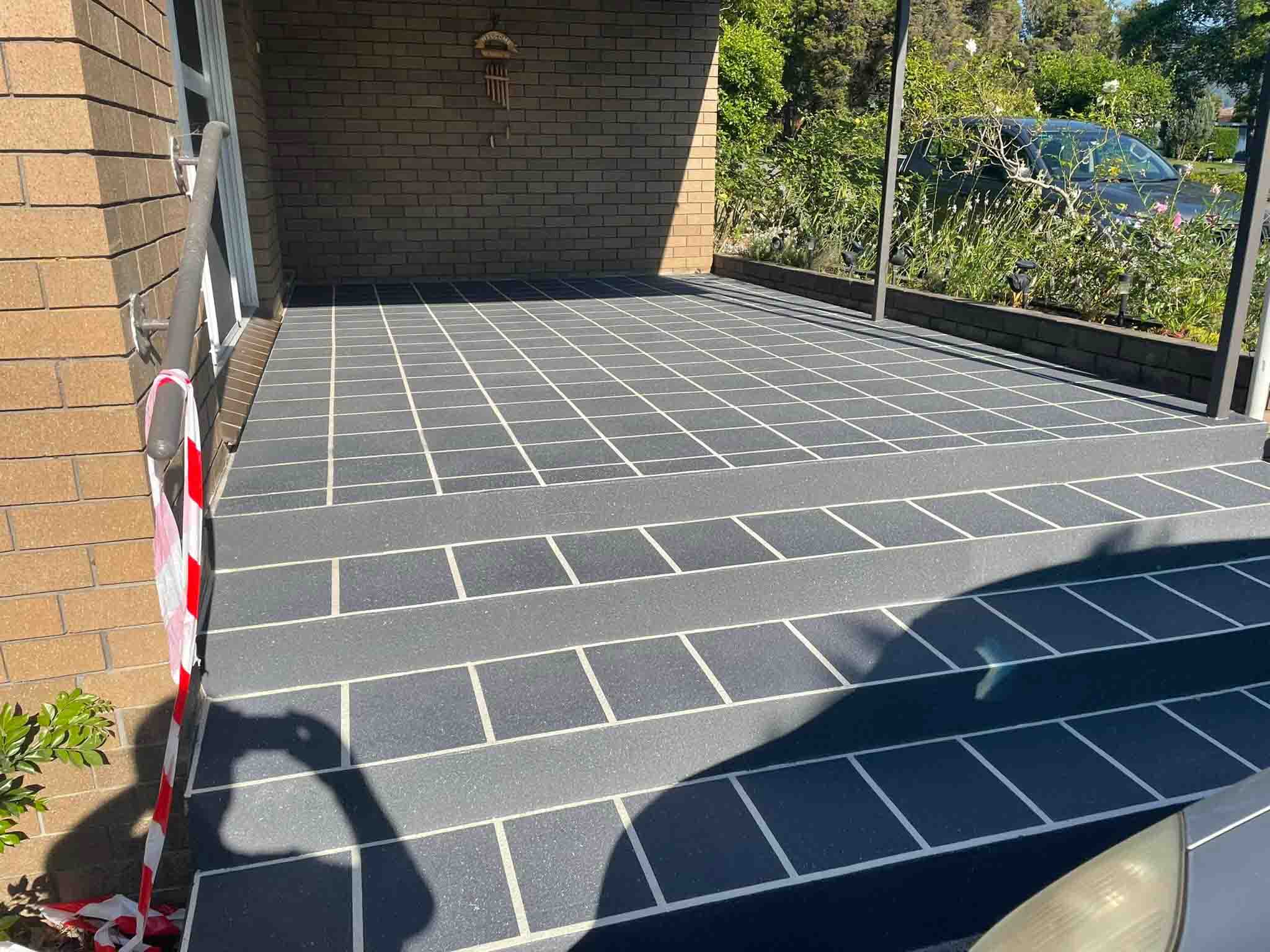 Grey tile-pattern resurfaced steps and porch at a brick house