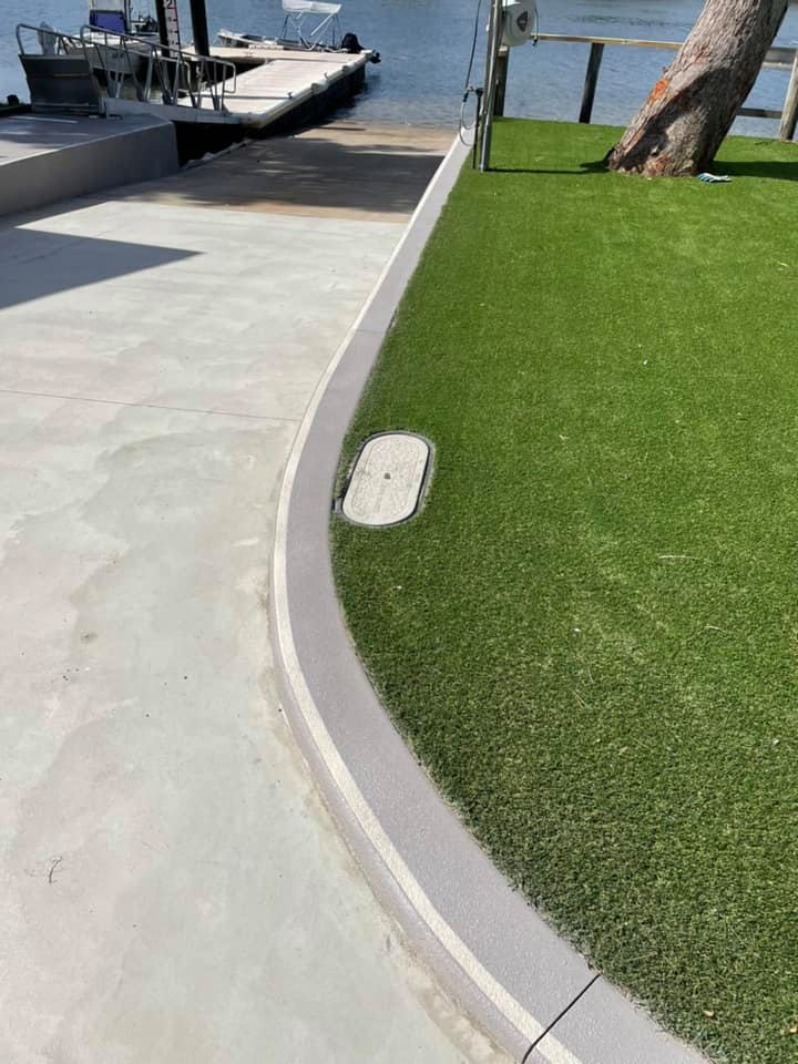 Curved concrete path beside artificial turf leading to a jetty