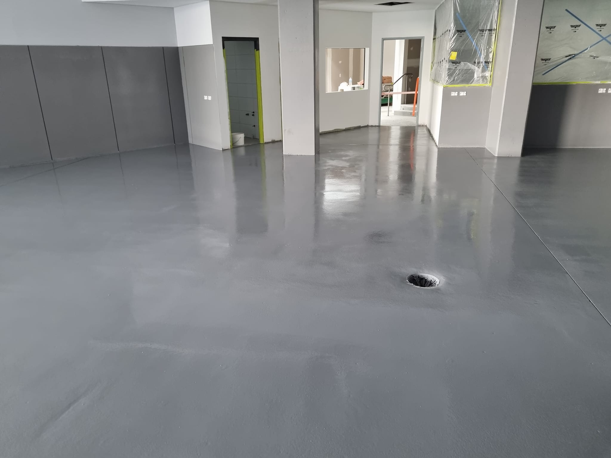 Glossy grey floor coating in a commercial space with the windows masked off