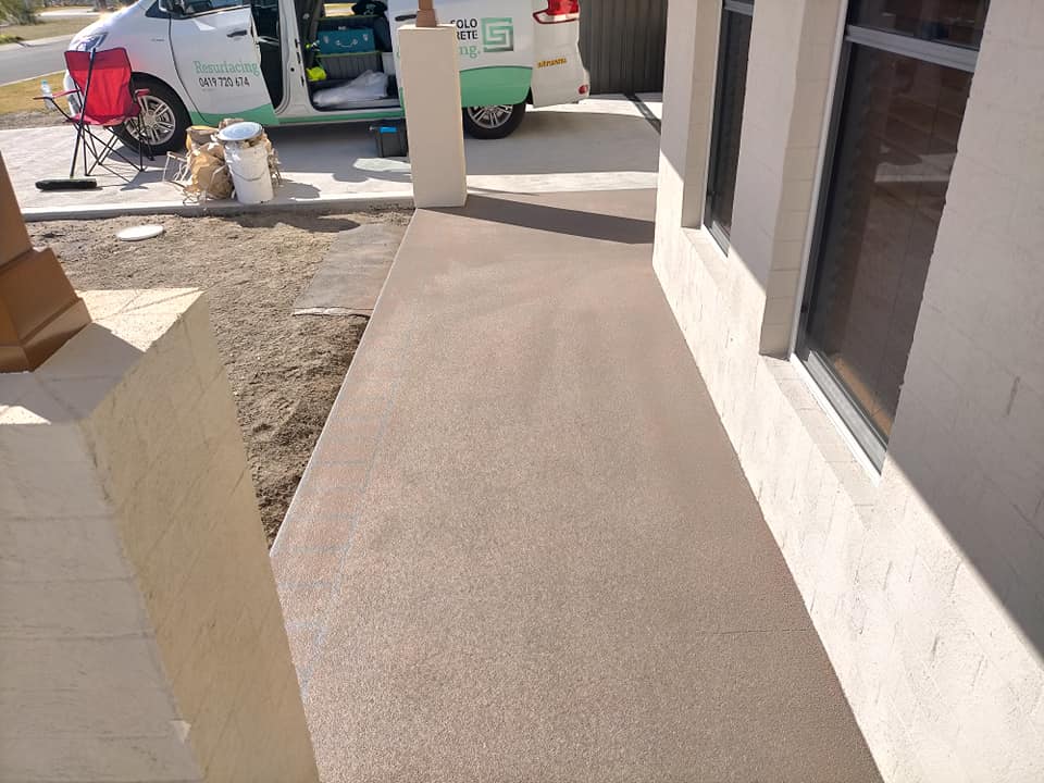 Freshly resurfaced path beside a new rendered house, work van behind