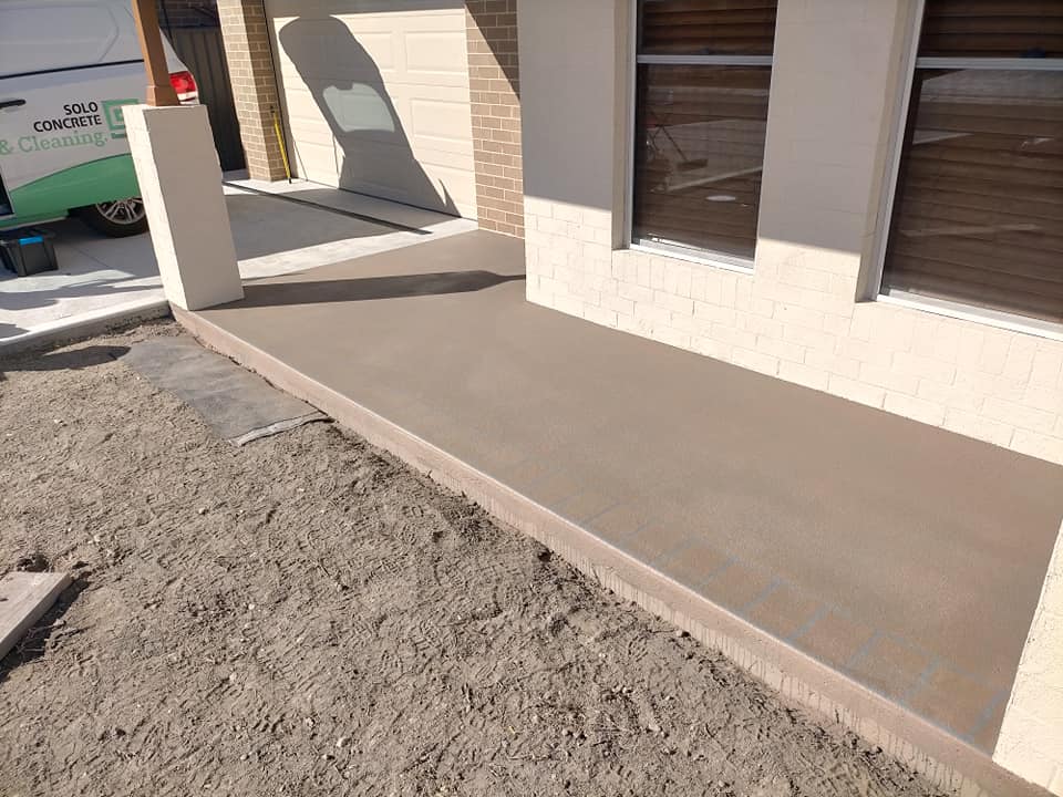 Resurfaced porch beside a new house, work van parked behind