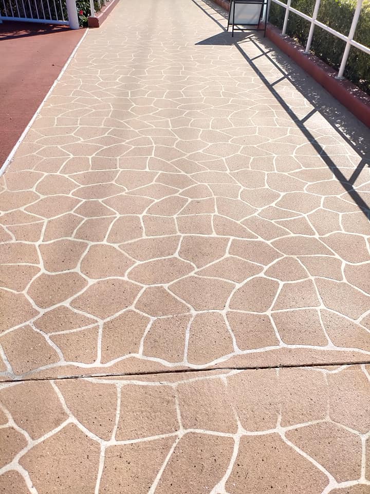 Sandstone-coloured crazy-paving pattern on a resurfaced path beside a railing