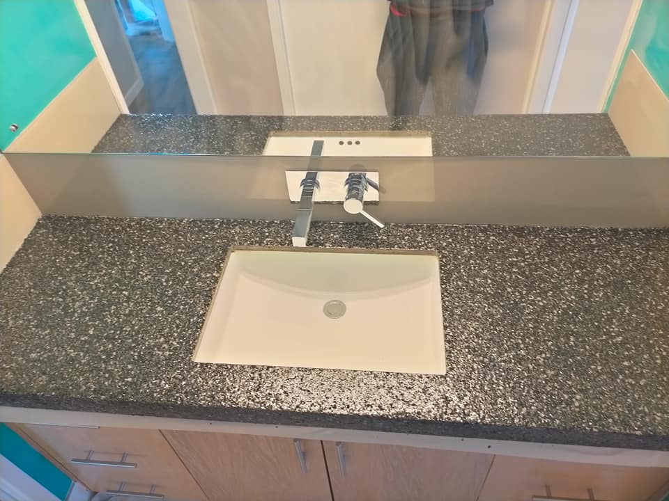 Speckled charcoal vanity benchtop with a white basin and wall tap