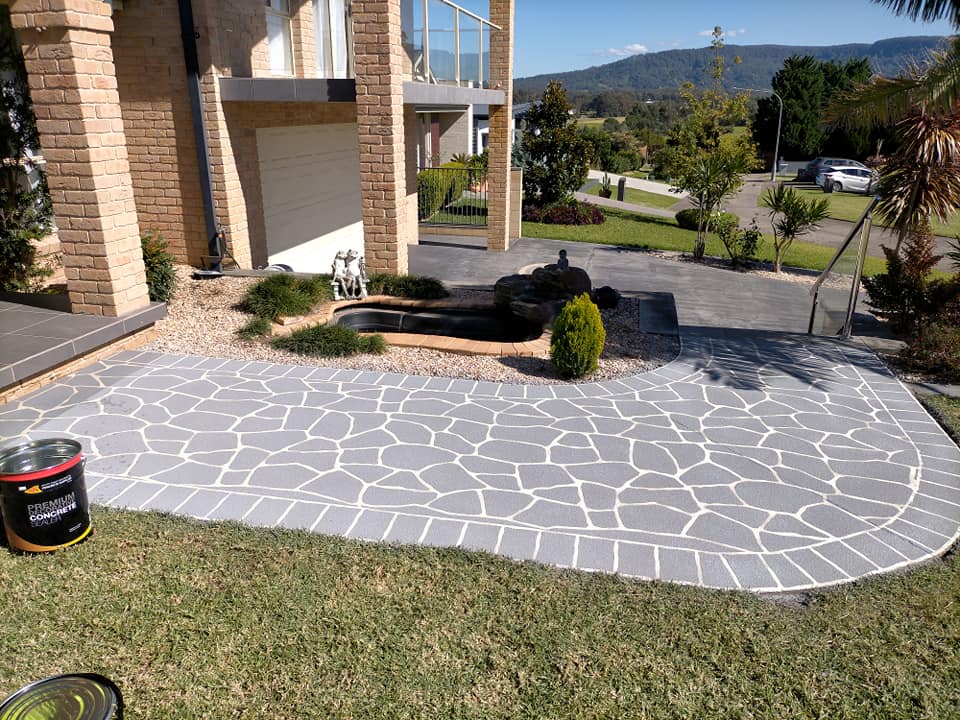Finished grey crazy-paving path curving across a front lawn