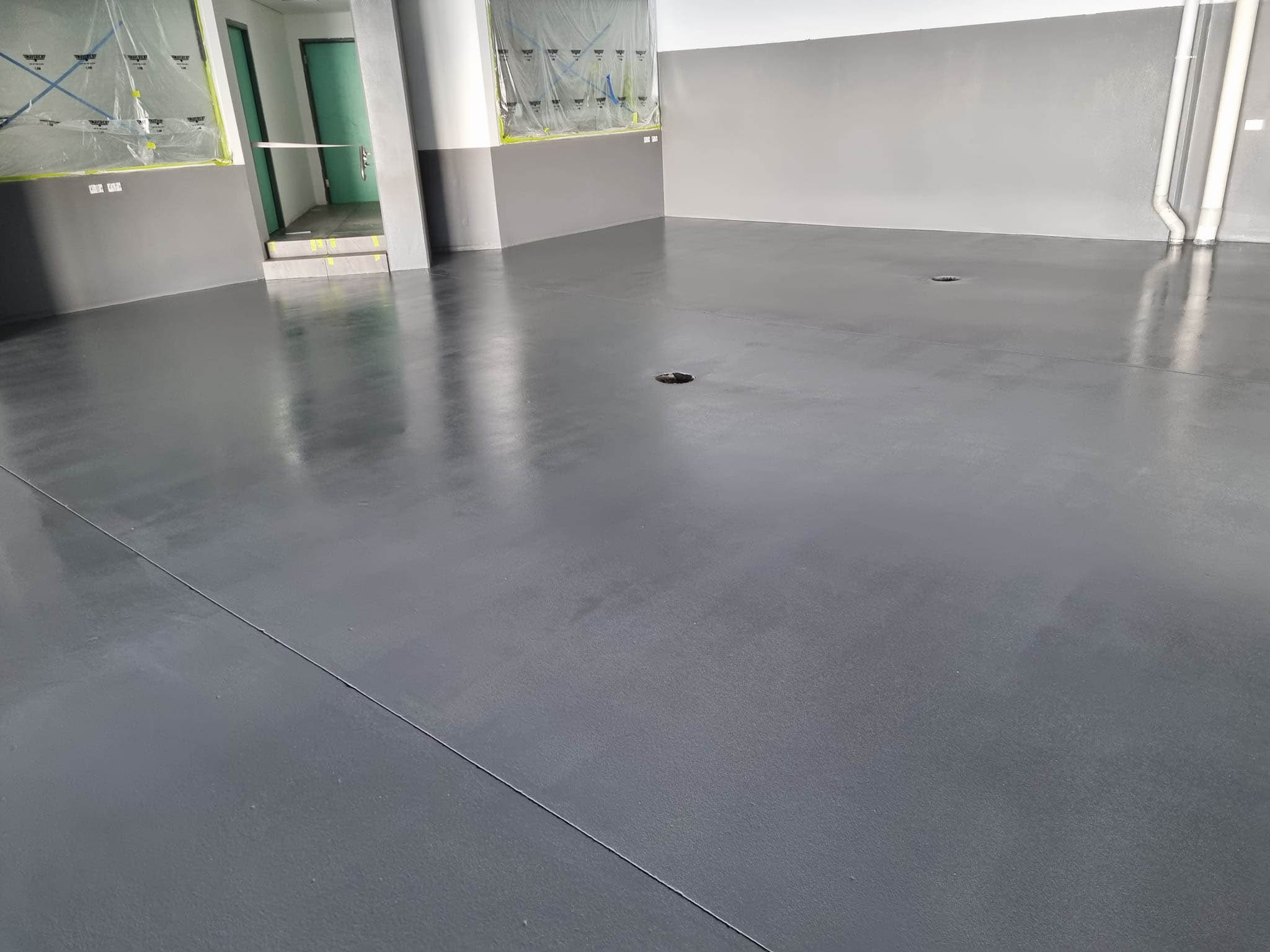 Glossy charcoal floor coating in a commercial space, looking towards green doors