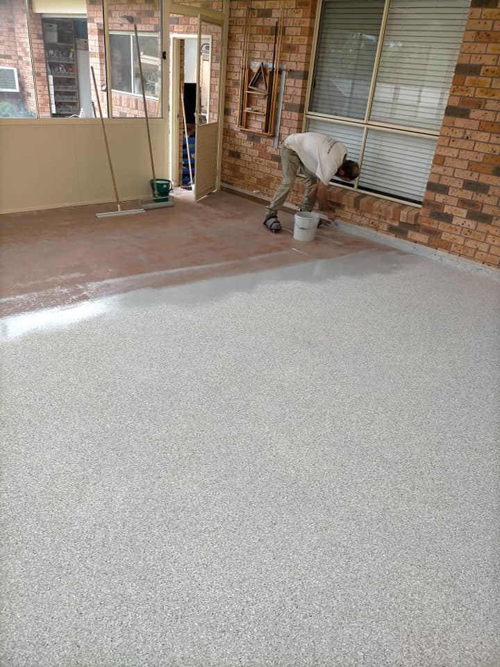 Worker applying a speckled coating over an old tiled sunroom floor