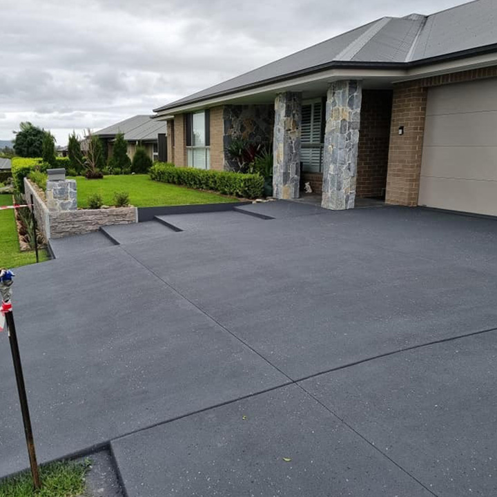 Charcoal resurfaced driveway and steps at a new brick home with stone pillars