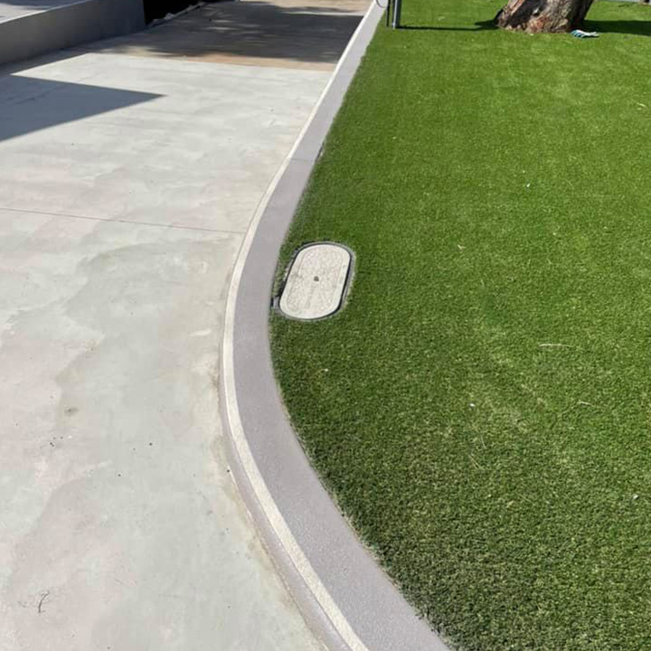 Curved concrete path edged beside artificial turf