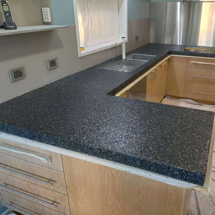 Kitchen with a speckled charcoal benchtop and stainless steel splashback