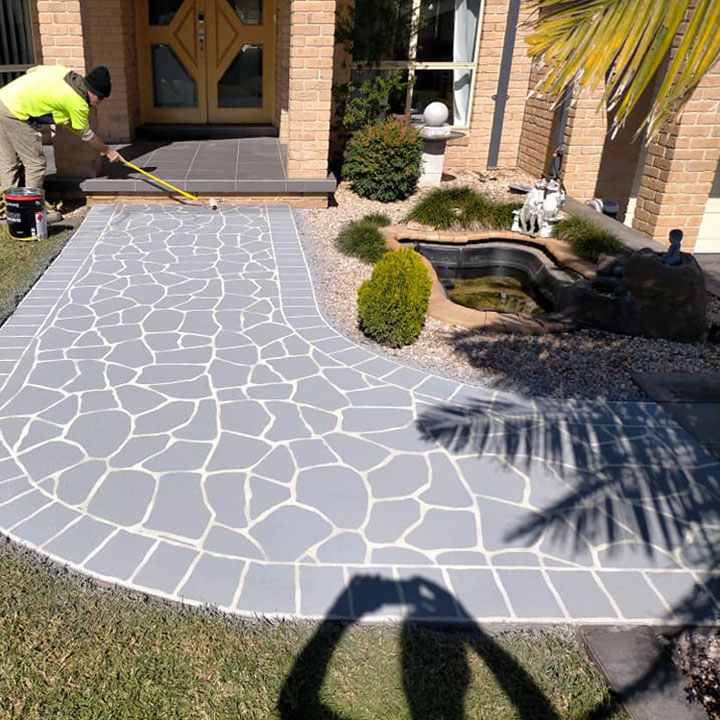 home-about3 Worker marking out a grey crazy-paving pattern on a resurfaced front path