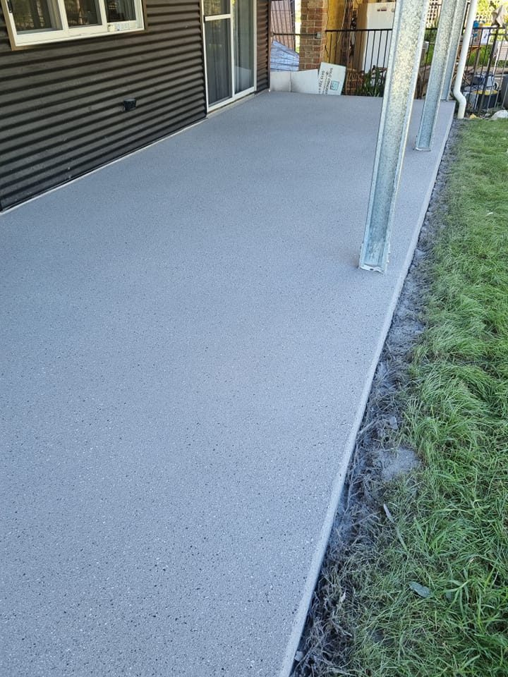 Speckled grey coating on a concrete veranda beside a house and lawn